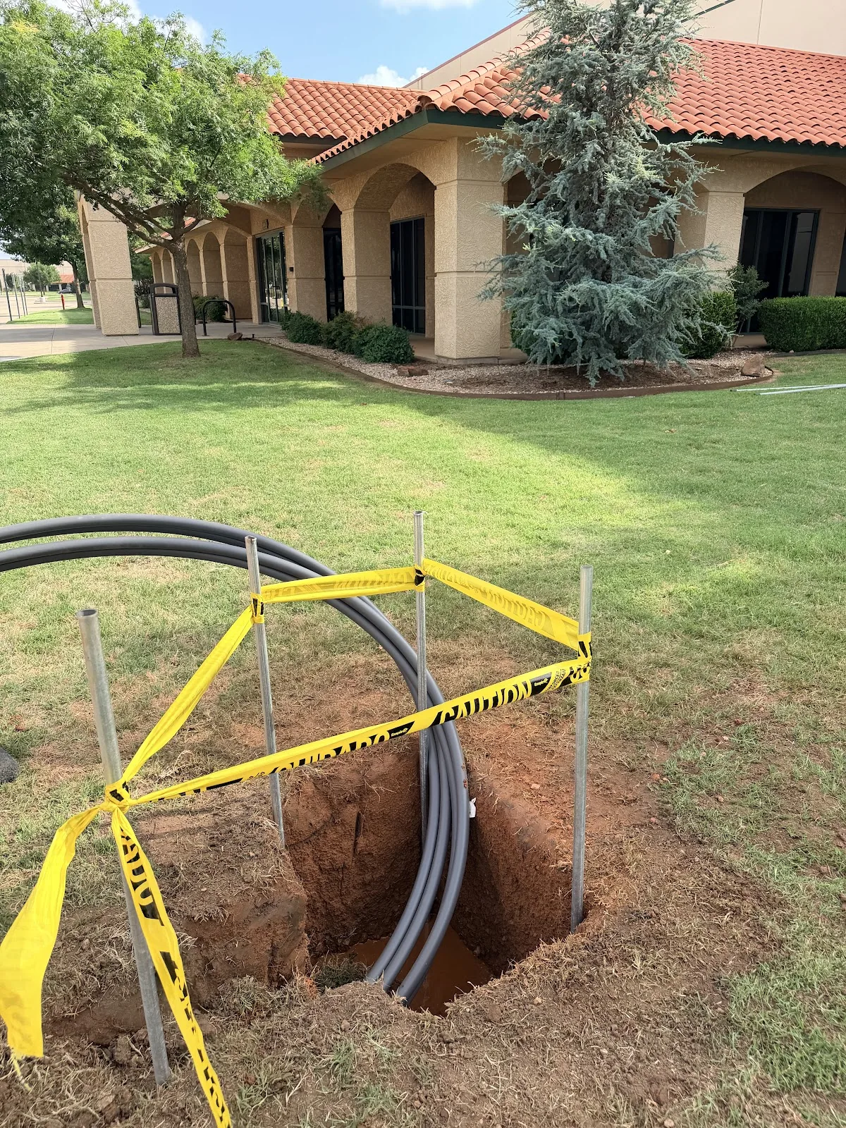 Trencher cutting an open-cut utility trench across a property