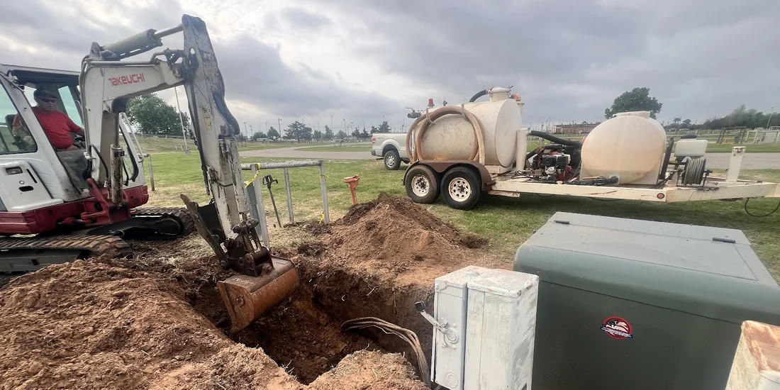 Mini-excavator working beside utility boxes for an underground electric conduit bore